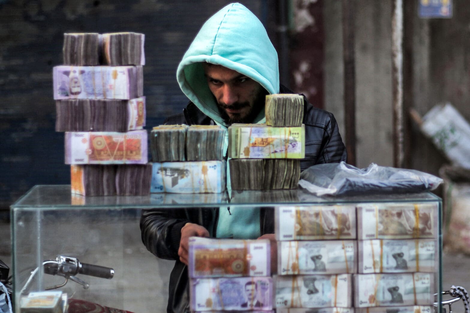 Stacks of Syrian pound banknotes are piled on top of each other at a currency trader's stall at a market in the city of Manbij, currently controlled by the Turkish-backed Syrian National Army faction, in Syria's northern Aleppo province on January 4, 2025. (Photo by Aaref WATAD / AFP)